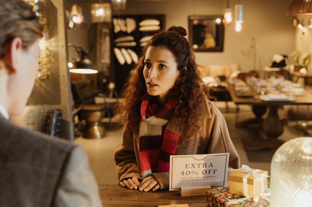 Woman in a boutique store discussing with a salesperson during a sale.